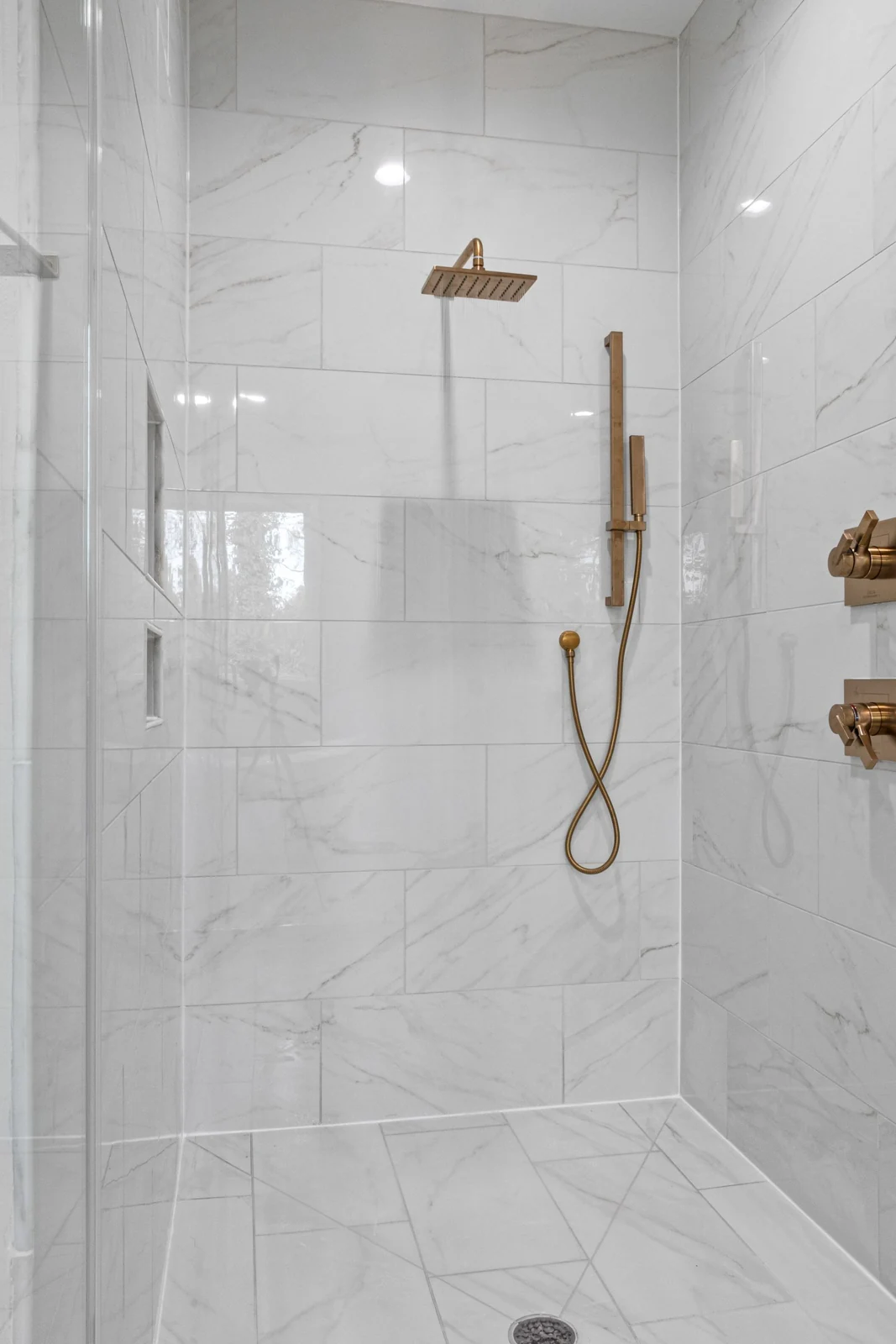 Elegant marble shower featuring contemporary gold fixtures and sleek design