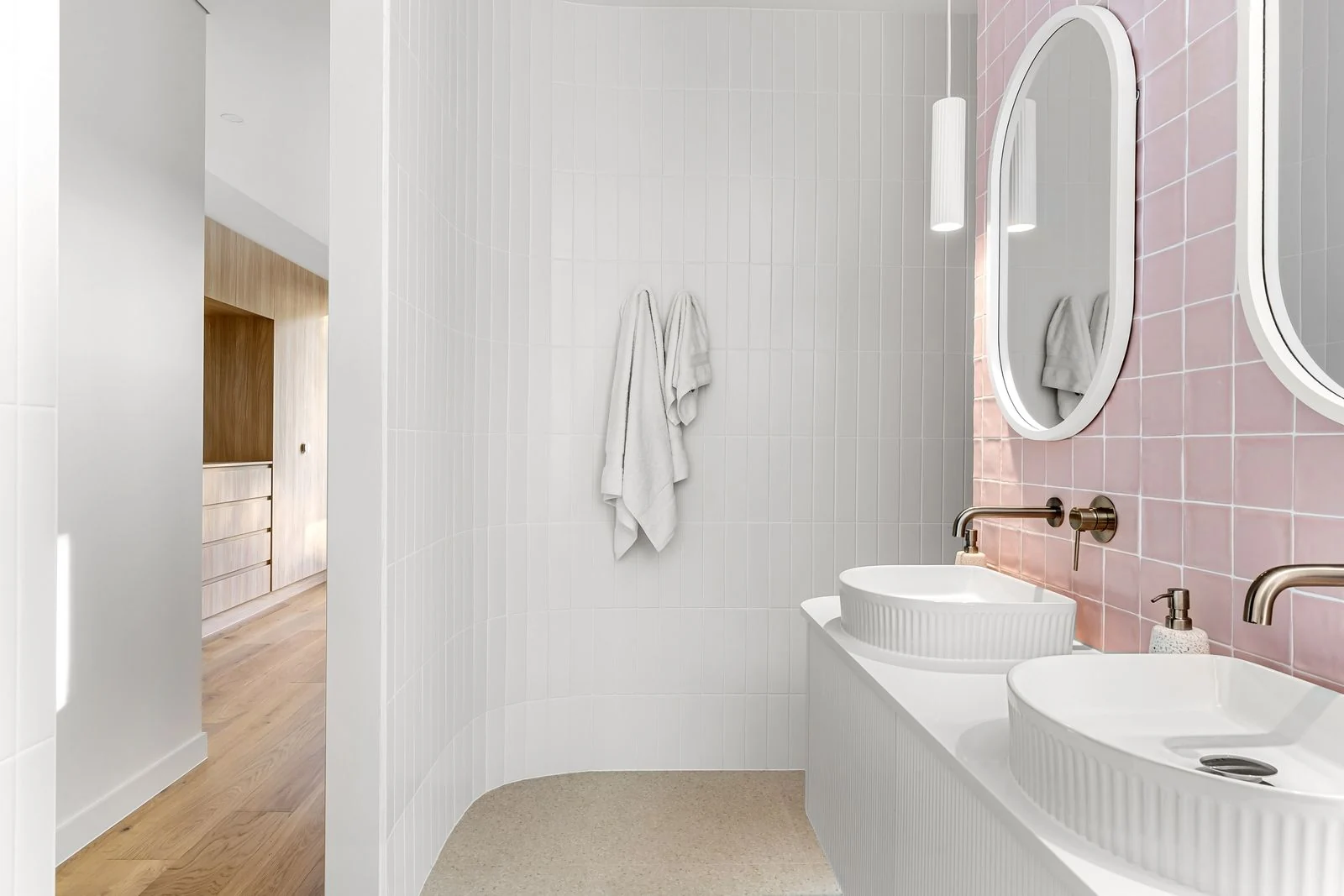 Elegant minimalist bathroom featuring pink tiles and dual sinks with modern fixtures
