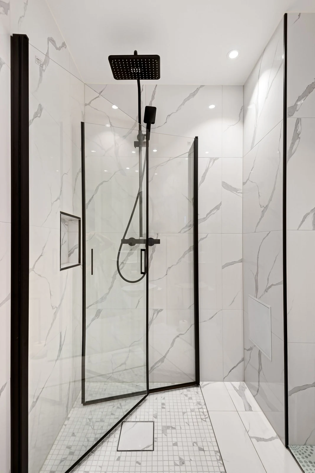 Elegant modern shower featuring sleek marble tiles and a glass door for a minimalist aesthetic
