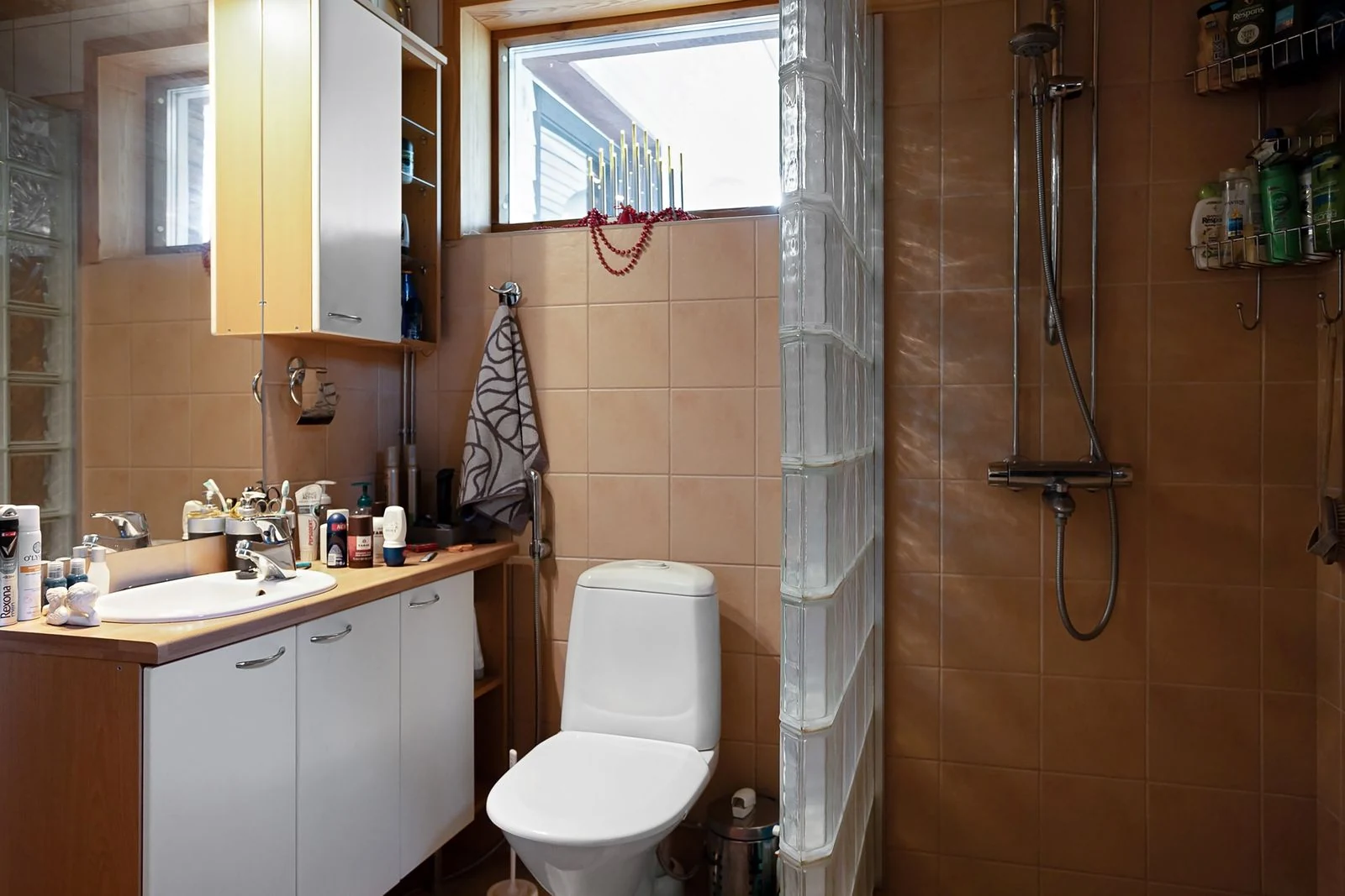A contemporary bathroom featuring a shower, sink, and vanity with natural light from the window