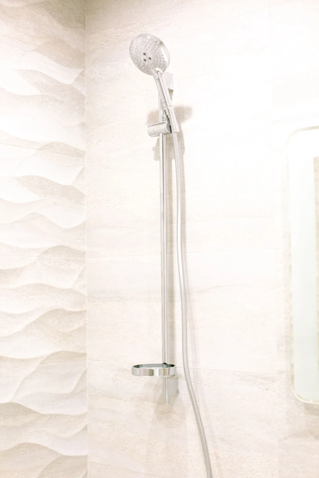 Bright white bathroom featuring a sleek shower head and textured wall design