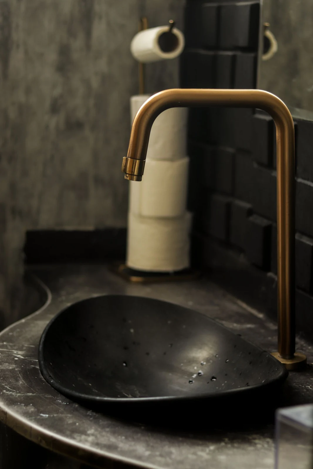 Dark bathroom basin and curved tap