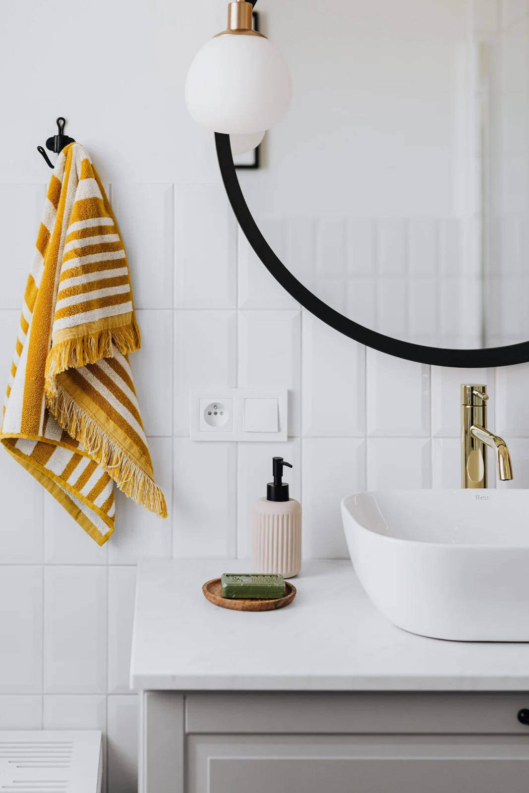 Basin beneath a round bathroom mirror