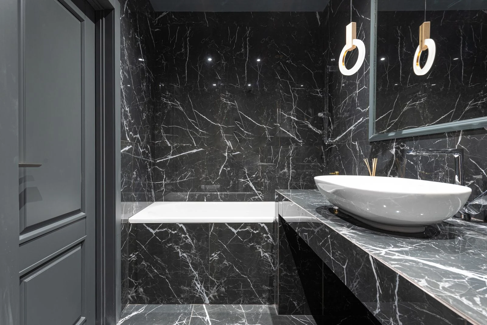 Stylish bathroom with bathtub and round lamp hanging above sink placed on marble surface