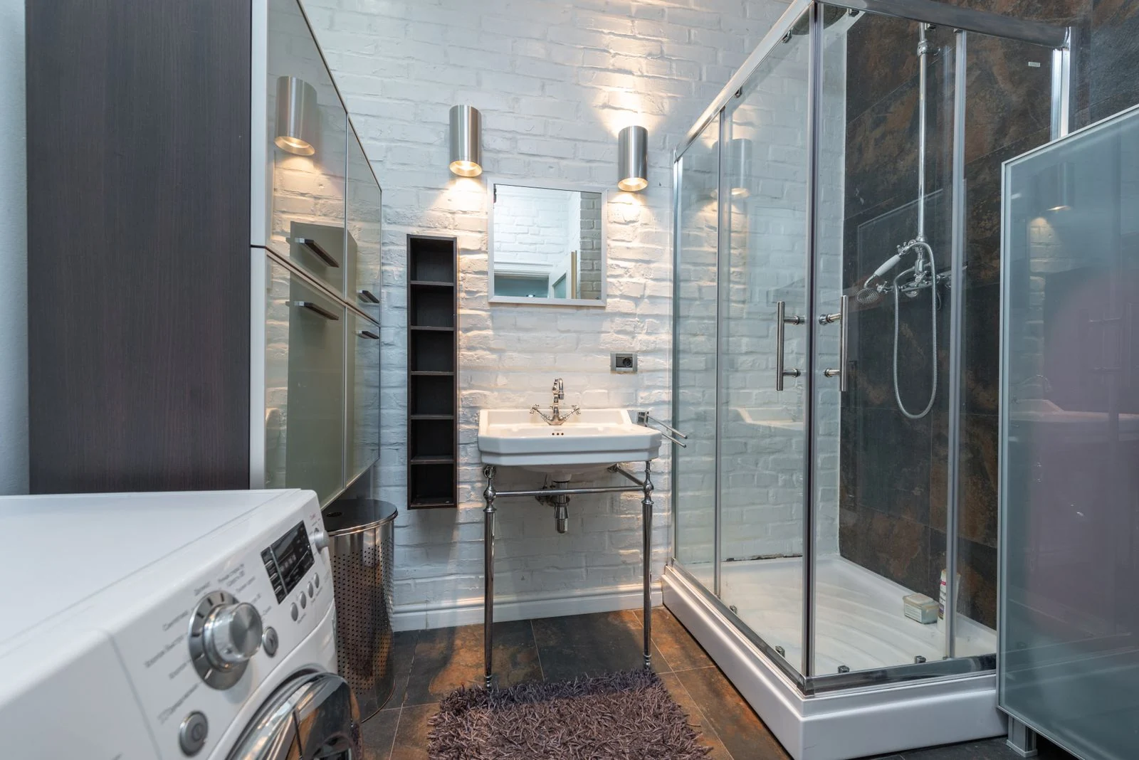 Sleek and contemporary bathroom showcasing a shower cabin, sink, and washing machine